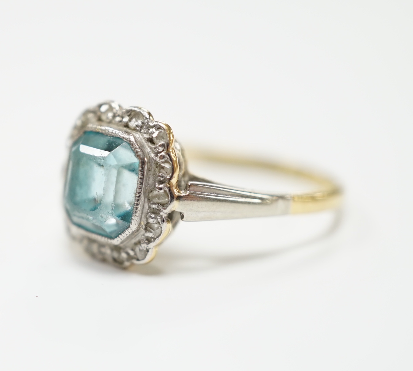 An 18ct and plat, blue zircon and diamond chip cluster set ring, size O, gross weight 3.4 grams.